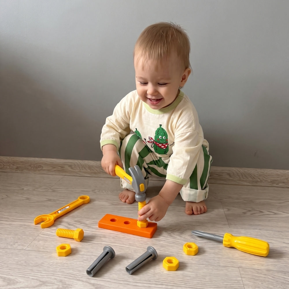 Niño jugando con herramientas de juguete y piezas de construcción